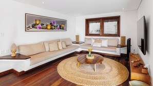 A modern living room with a sectional sofa, a round coffee table, and a large framed artwork on the wall. - Deluxe King Suite at Villa Lux Do Mar (Jijoca de Jericoacoara)