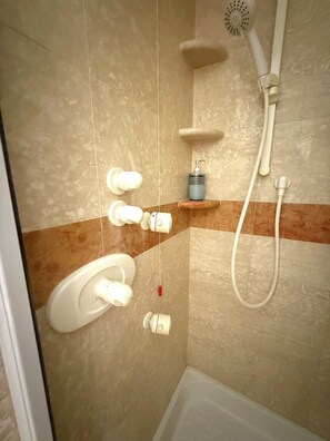 Un baño con ducha, inodoro y dispensador de jabón.