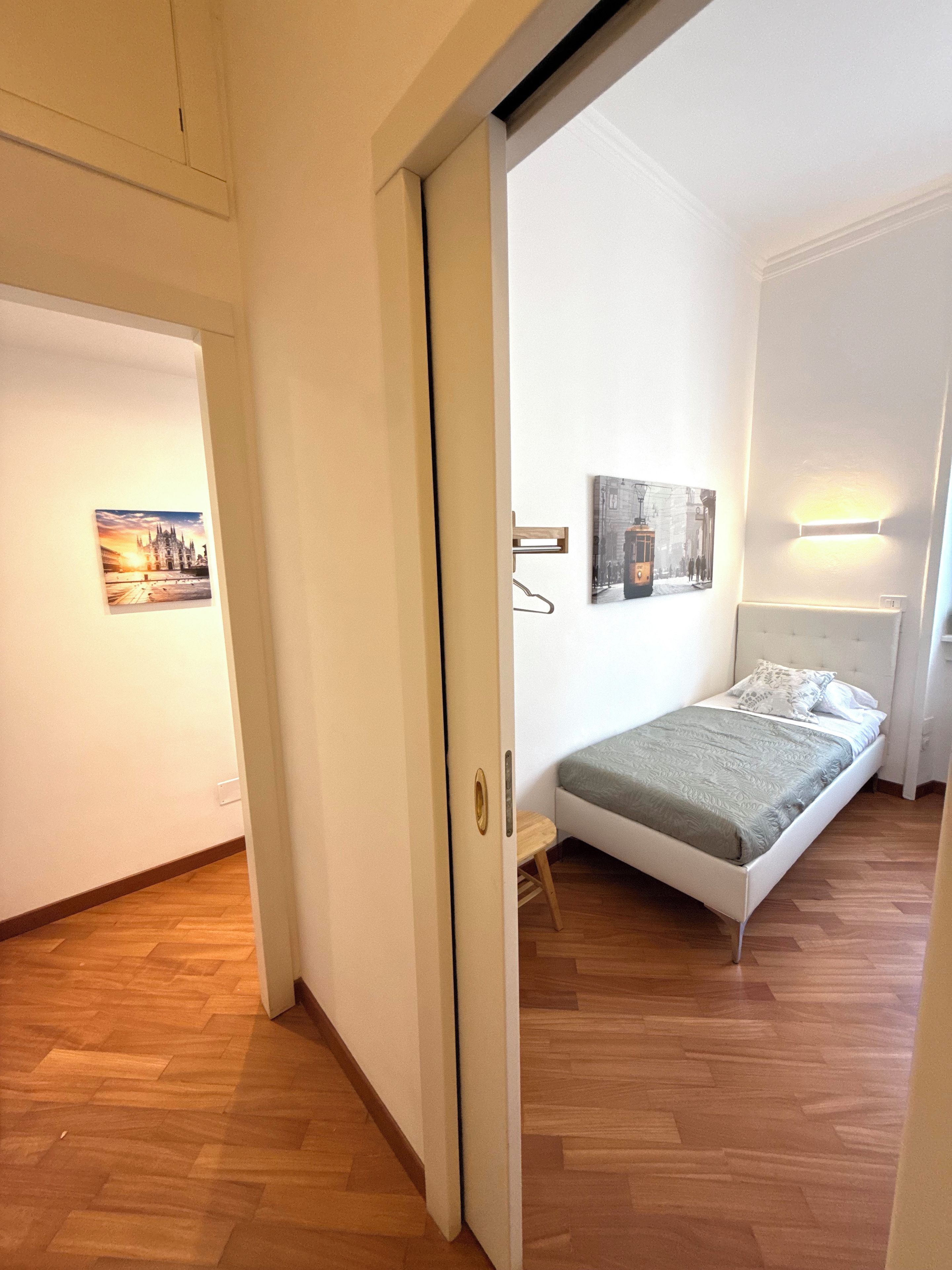 A bedroom with a bed, a small stool, and two wall-mounted light fixtures.