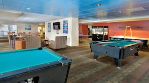 A pool table area with a billiards table, a seating area with striped chairs, and a snack bar.
