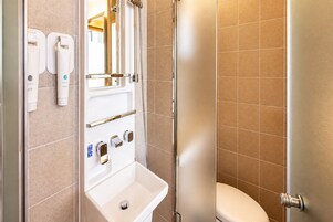 Un baño con lavamanos, espejo y dispensador de artículos de aseo.
