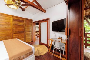 Ein Zimmer mit einem Bett, einem Schreibtisch mit Stuhl, einem Fernseher und Holztüren.