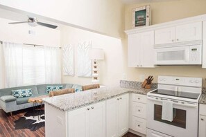 Una cocina pequeña con gabinetes blancos, un microondas y un horno.