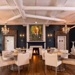 A dining area with round tables, white chairs, and a fireplace. - Cozy Jasmine Cottage | Savannah + Tybee l Cohens Retreat (Savannah)