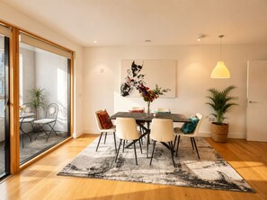 Ein Essbereich mit Tisch, Stühlen, einer Vase mit Blumen und einem Gemälde an der Wand.