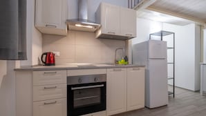 A modern kitchen with white cabinetry, a built-in oven, a stainless steel range hood, and a white refrigerator. - Caduti di Via Fani by Wonderful Italy (Bologna)