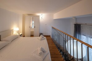 Une chambre d’hôtel avec un grand lit, un escalier en bois et une vue sur l’extérieur.