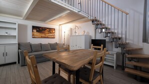 A modern living space with a dining area, sofa, and a staircase with a railing. - Caduti di Via Fani by Wonderful Italy (Bologna)