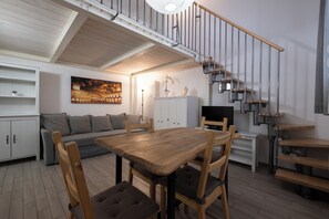A modern living space with a dining area, sofa, and a staircase with a railing. - Caduti di Via Fani by Wonderful Italy (Bologna)