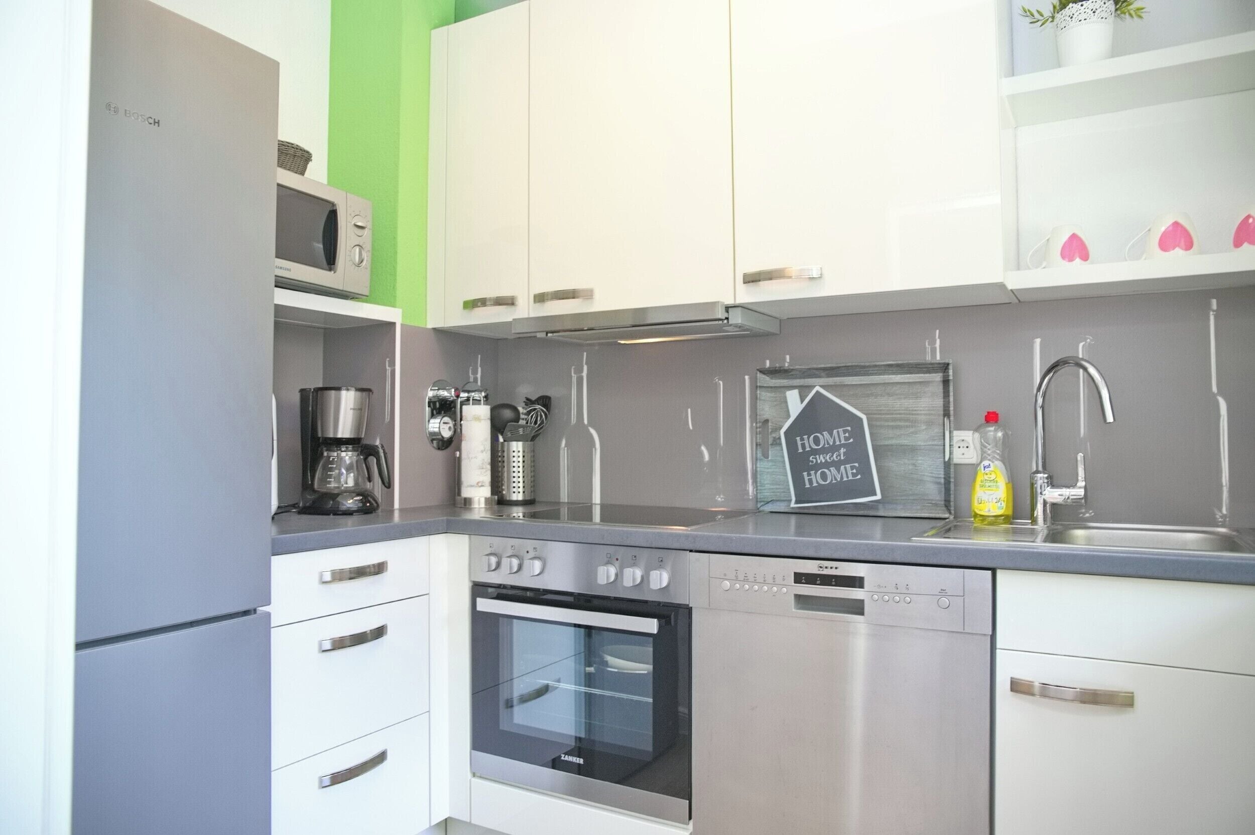 A modern kitchen with white cabinets, a stainless steel range, a built-in oven, and a coffee maker.