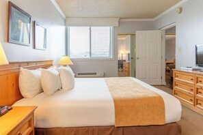 Ein Hotelzimmer mit einem großen Bett, einem Nachttisch, einer Lampe, einem Fernseher und einem Kleiderschrank.