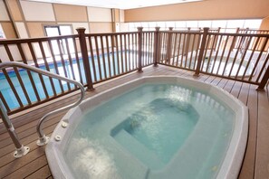 Ein beheiztes Hallenbad mit Whirlpool, Holzboden und Metallgeländer.