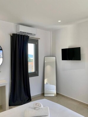 Une chambre d’hôtel équipée d’un lit, d’un téléviseur à écran plat, d’un grand miroir et d’un appareil de climatisation.