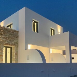A modern two-story building with a flat roof and a stone facade on one side. - Aitheria Suites Ios (Ios)