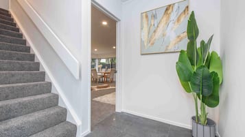 A staircase leading to a dining area with a large plant and a framed artwork on the wall.