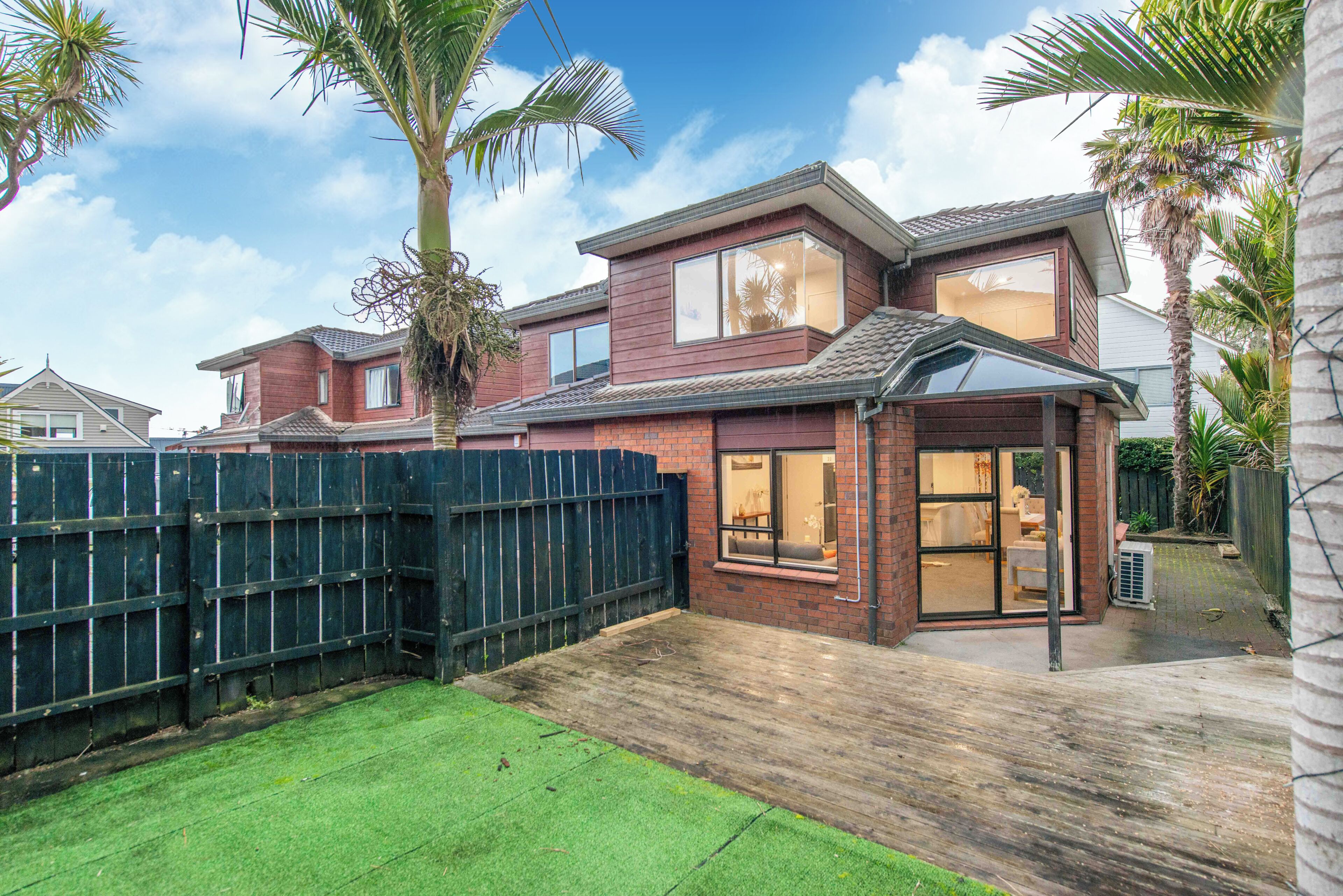 A two-story house with a fenced backyard, large windows, and a visible garage.