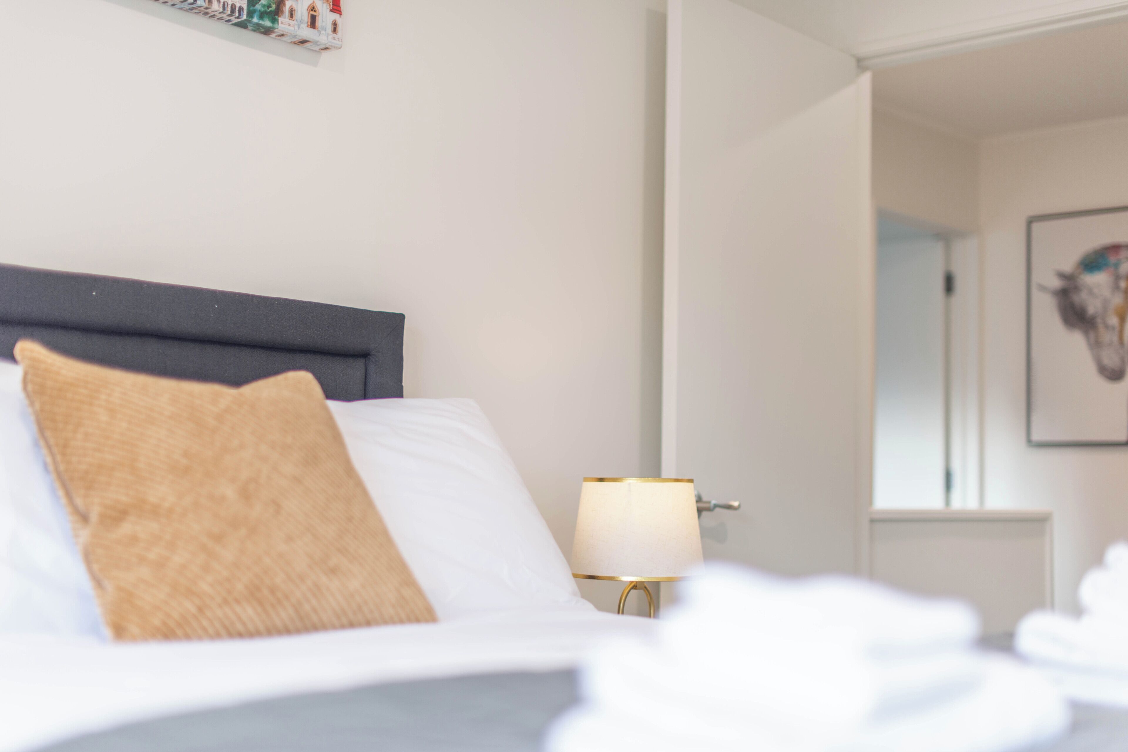 A neatly made bed with a single pillow and a bedside lamp.