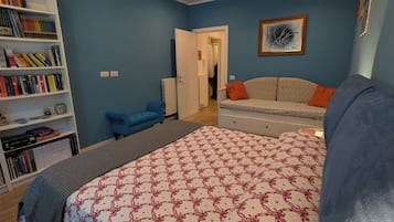 Ein Schlafzimmer mit Bett, Bücherregal, Sofa und einer Tür zu einem anderen Raum.