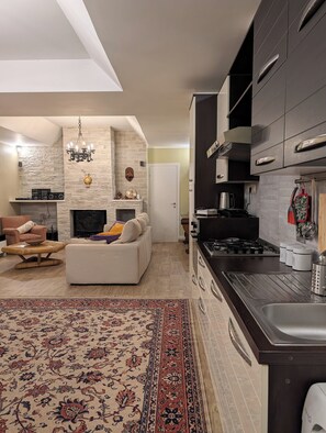 A modern living room with a fireplace, a sofa, and a dining area with a kitchen in the background.
