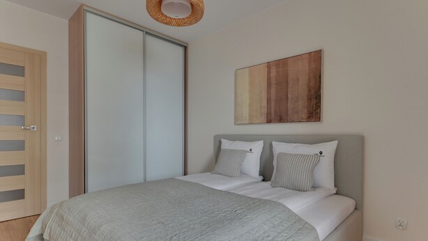 Quarto com cama, guarda-roupa, um quadro e luminária.