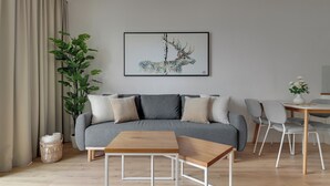 Uma sala de estar moderna com um sofá cinzento, uma mesa de centro de madeira e uma planta em vaso.