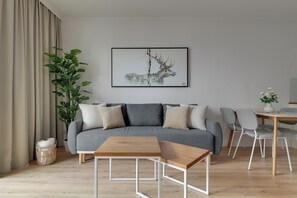 Una sala de estar moderna con un sofá gris, una mesa de centro de madera y una planta en maceta.