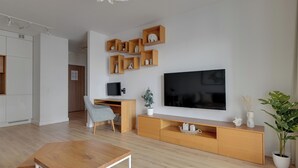 Uma sala de estar moderna com um suporte de TV de madeira, uma TV de tela plana, uma escrivaninha e uma cadeira.