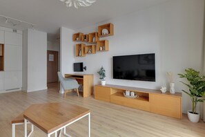 Una sala de estar moderna con un mueble de televisión de madera, un televisor de pantalla plana, un escritorio y una silla.