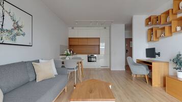 Ein modernes Wohnzimmer mit grauem Sofa, einem Holztisch und einem Essbereich mit weißem Tisch und Stühlen.