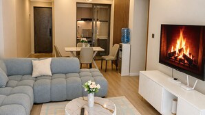 A modern living room with a sectional sofa, a round coffee table, a flat-screen TV, and a dining area with a table and chairs.