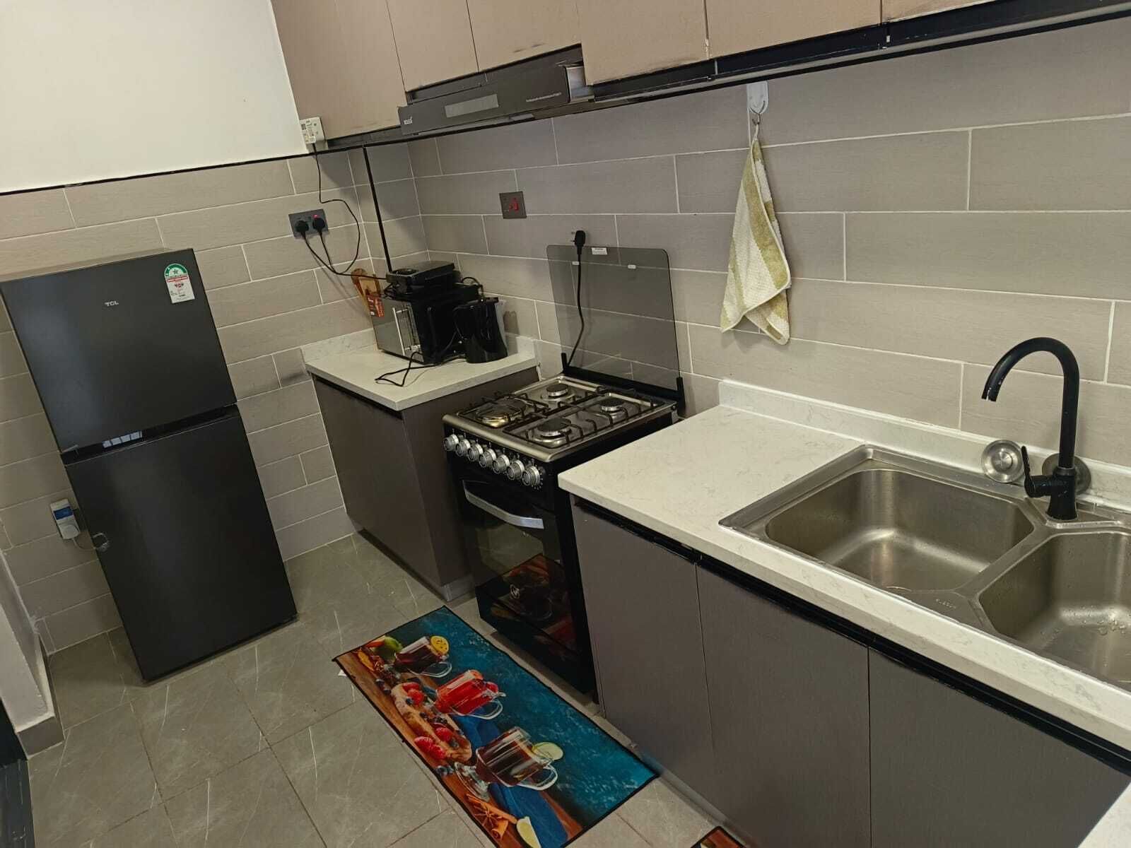 Una cocina compacta con refrigerador, estufa y lavamanos.