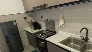 A compact kitchen with a refrigerator, stove, and sink.