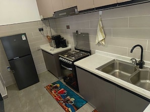 Una cocina compacta con refrigerador, estufa y lavamanos.
