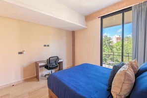 Ein Hotelzimmer mit Bett, Schreibtisch und Blick ins Freie.