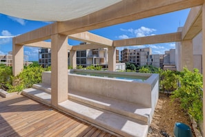 Eine Dachterrasse mit Pool, Betonbauten und umgebender Bepflanzung.