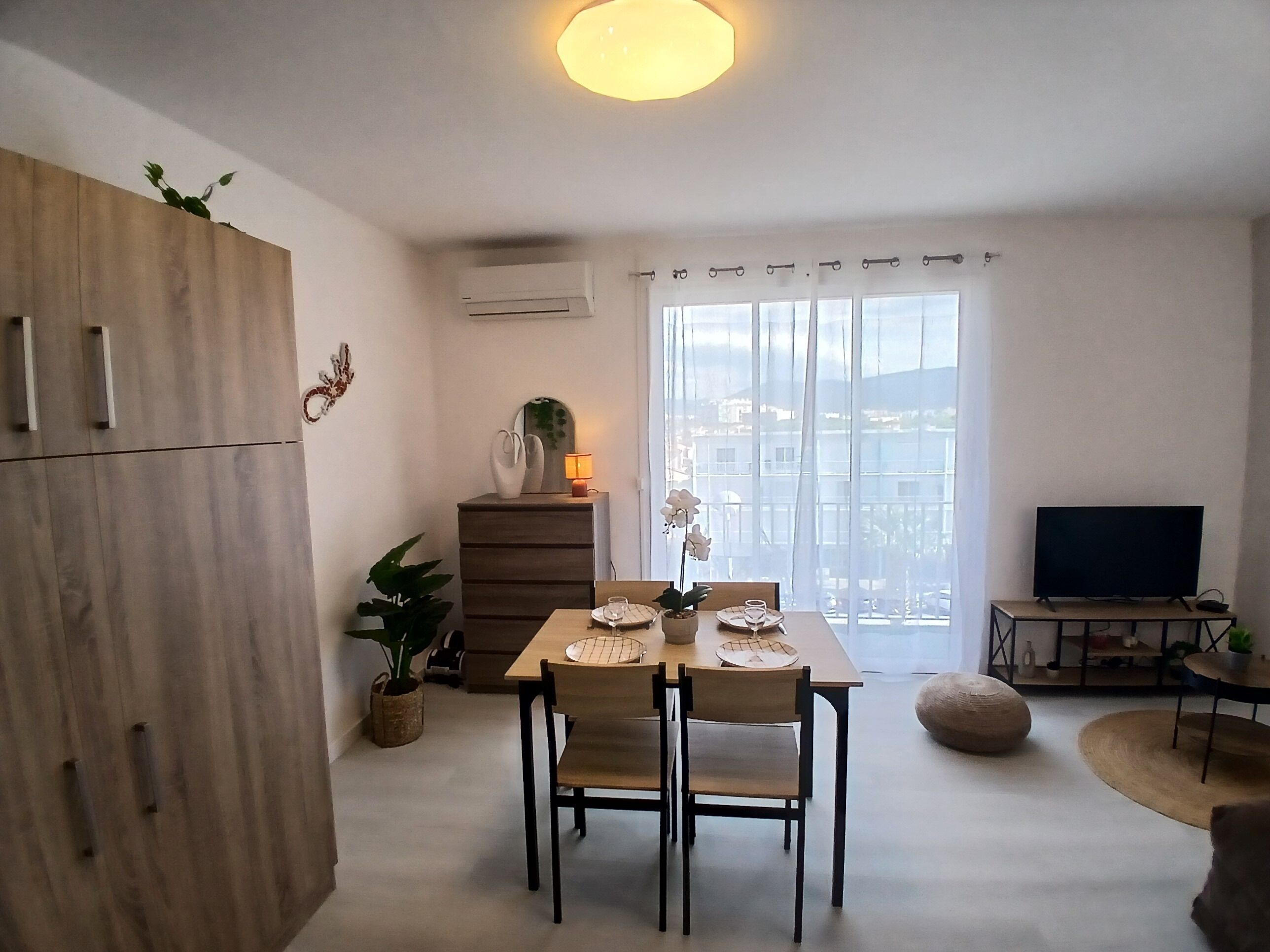 Moderni olohuone, jossa on ruokailutila, televisio ja parveke, jolta on näkymä.