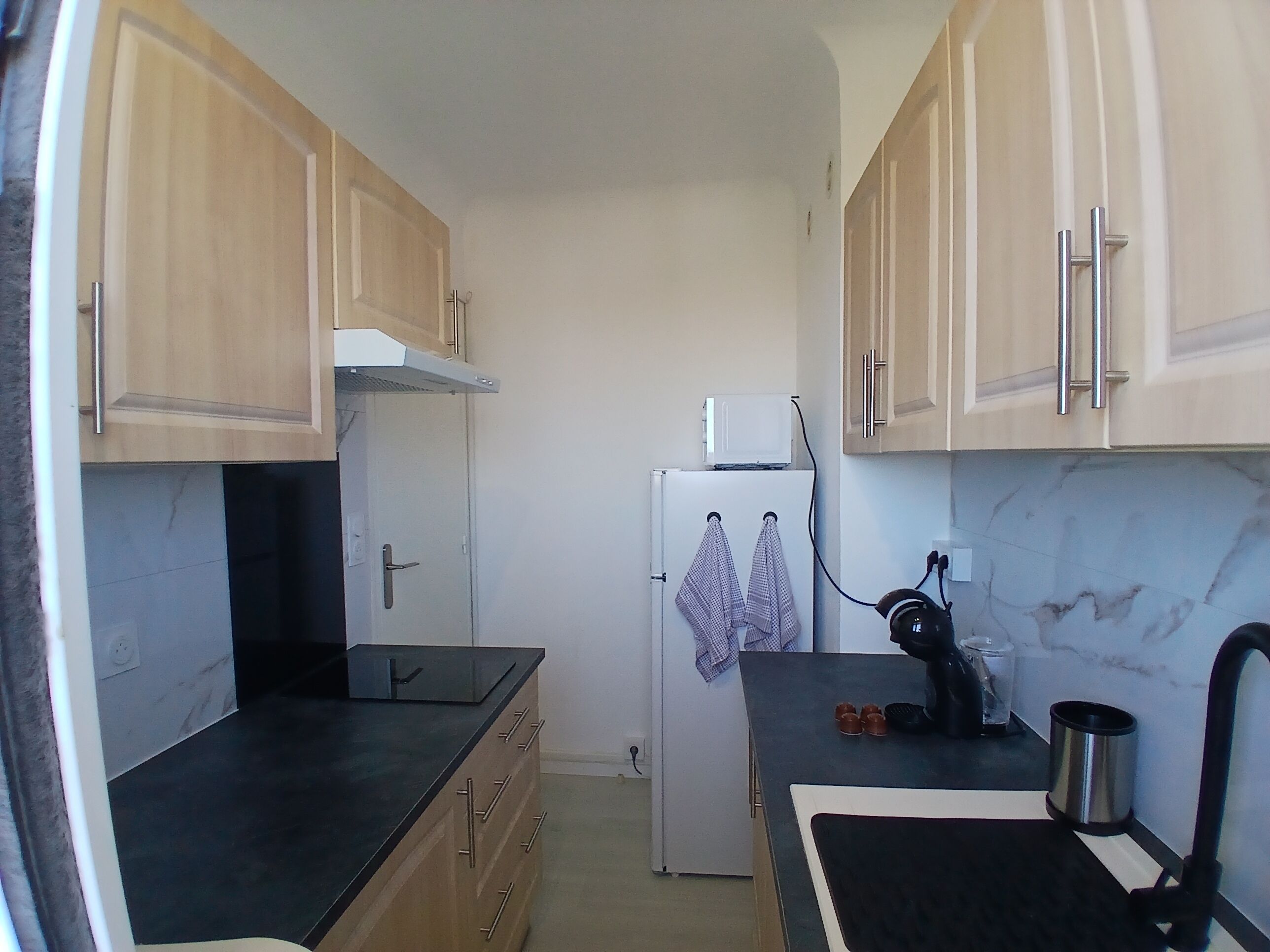 A compact kitchen with wooden cabinets, a white refrigerator, and a black countertop.