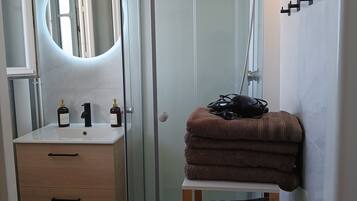 Un baño moderno con cabina de ducha de vidrio, tocador con espejo y perchero.