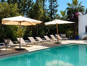 Ein Schwimmbecken mit Liegestühlen und Sonnenschirmen.
