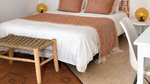 Ein ordentlich eingerichtetes Schlafzimmer mit Bett, Nachttischen, einer Bank und einem gemusterten Teppich.