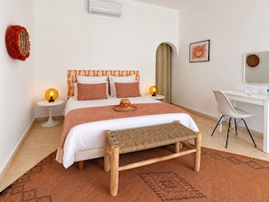 Een moderne slaapkamer met een bed, nachtlampjes, een bureau en een stoel.