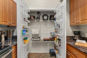 A kitchen with wooden cabinets, white shelving units, and various kitchen appliances. - 3BR Mesa Getaway | Pool, Hot Tub, Gym, Clubhouse, Basketball + Room for the Whole Family (Mesa)