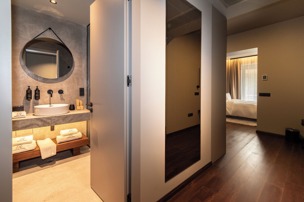 A hotel bathroom with a sink, mirror, and toiletries.
