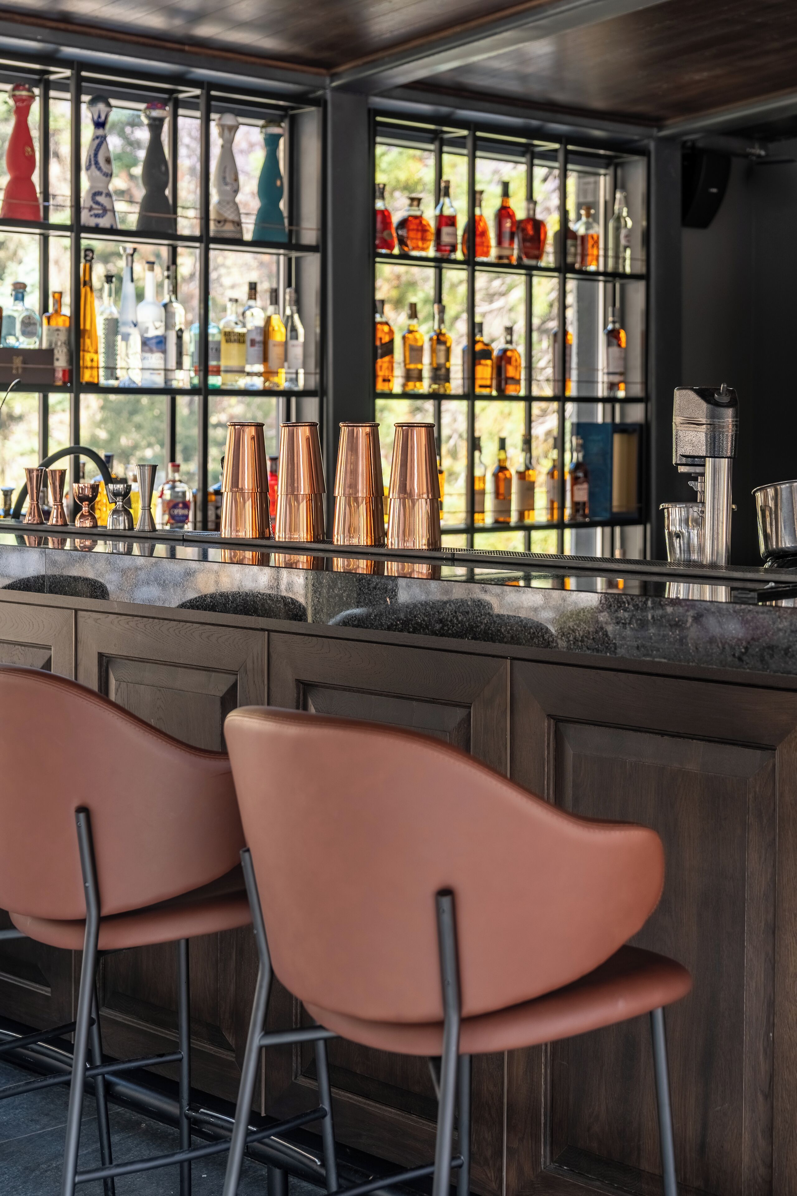 Un espace bar avec un comptoir, des chopes en cuivre et une variété de bouteilles.