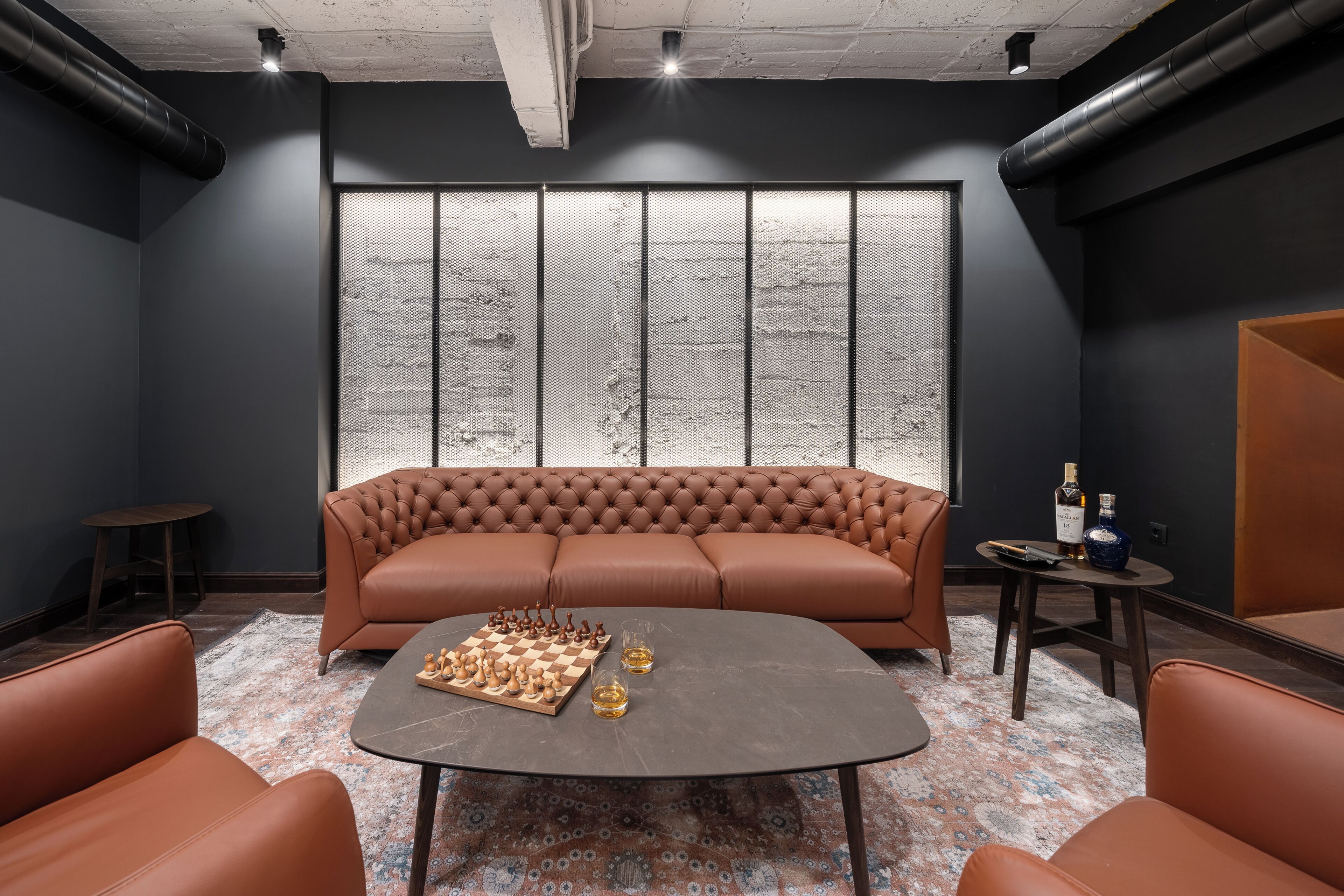 Un salón moderno con un sofá de cuero, una mesa de ajedrez y una alfombra estampada.