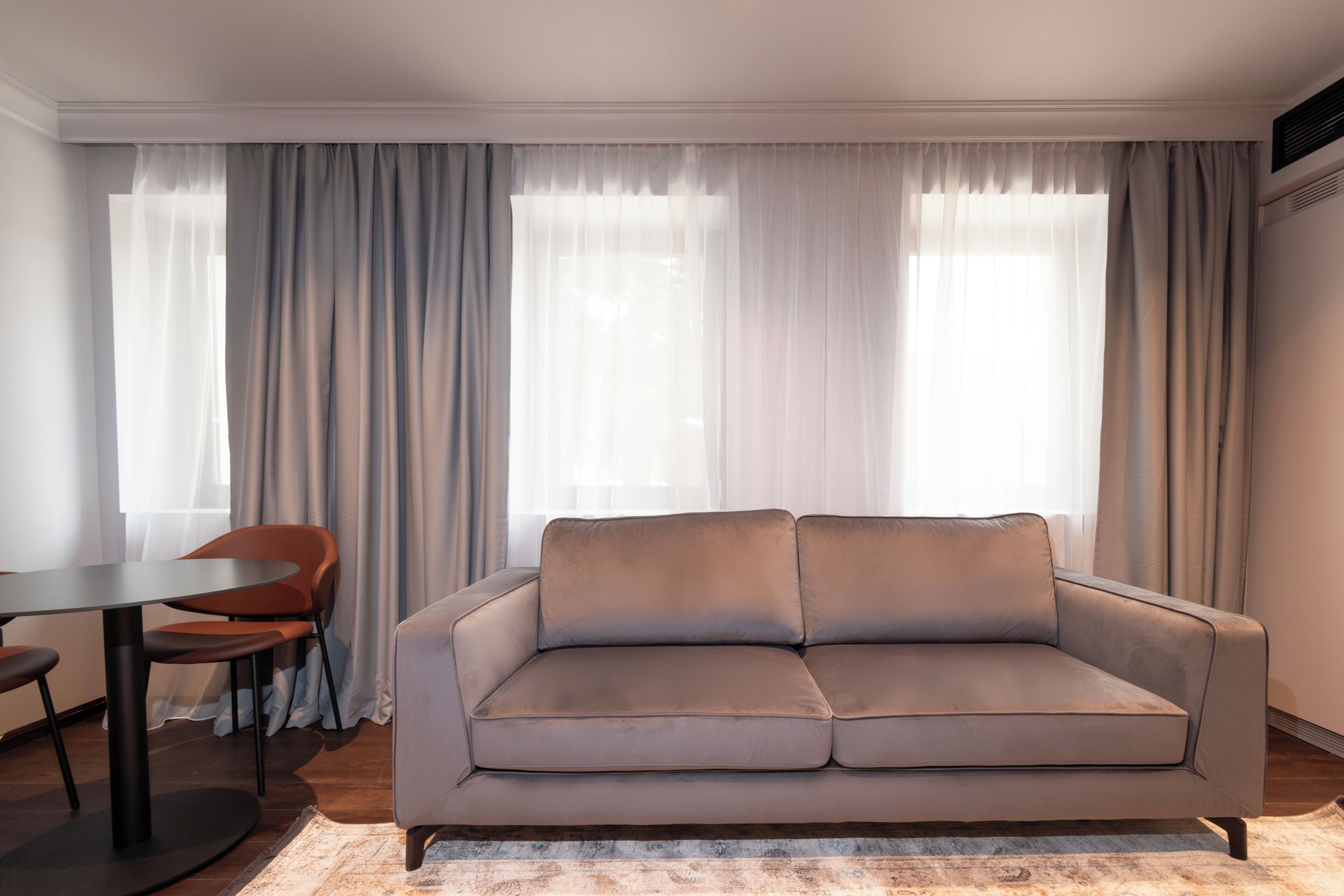 A modern living room with a sofa, a dining table, and chairs.