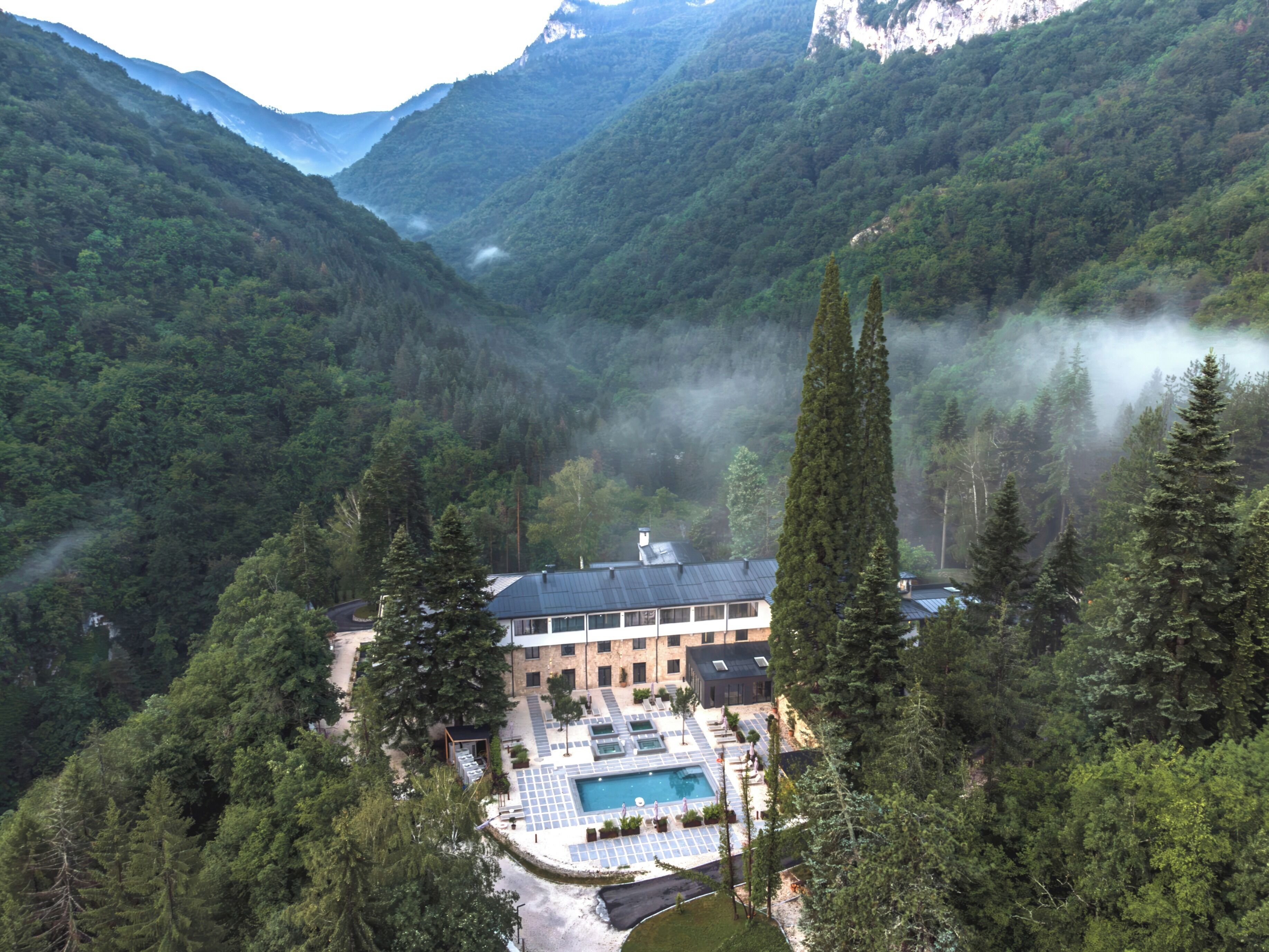 A resort with a swimming pool, surrounded by forested mountains.