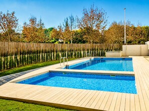 A rectangular swimming pool with a wooden deck surrounding it, a metal ladder, and a wooden fence in the background. - La Haya Penthouse Javea Arenal (Javea)