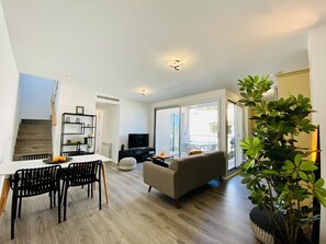 Ein modernes Wohnzimmer mit einer Couch, einem Esstisch, Stühlen und einem Fernseher.