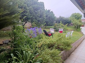 Um jardim com diversas plantas e uma área de estar com cadeiras e uma mesa.